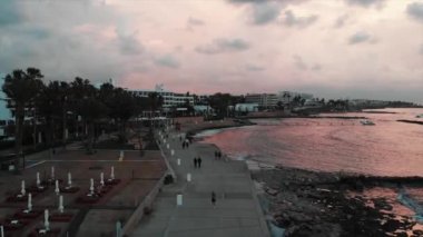 Gün batımında avuç içi ve plaj ekipmanları ile yaya gezinti havadan görünümü. Akdeniz yakınlarında yürüyen insanlarla turistik alanın Drone çekimi