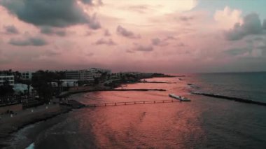 Gün batımında kayalık plaj isabet deniz dalgaları ile güzel rıhtım havadan drone görünümü