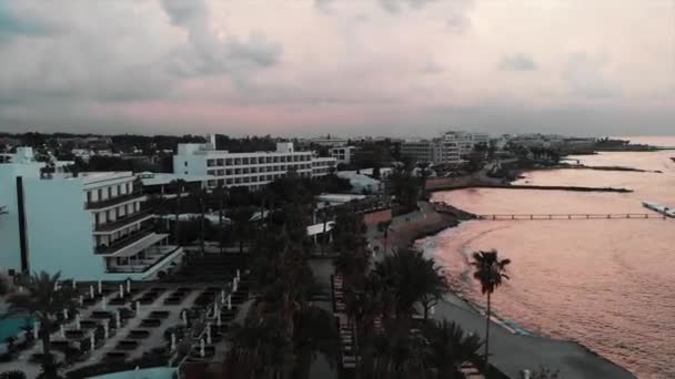 无人机在旅游区附近飞行，在日落时有酒店和棕榈树 — 图库视频影像