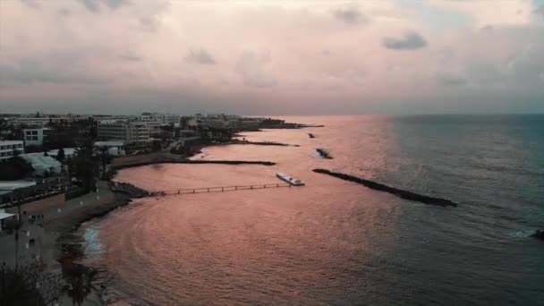 Letecký pohled na oceán při západu slunce s skalnatou pláží a promenádou — Stock video