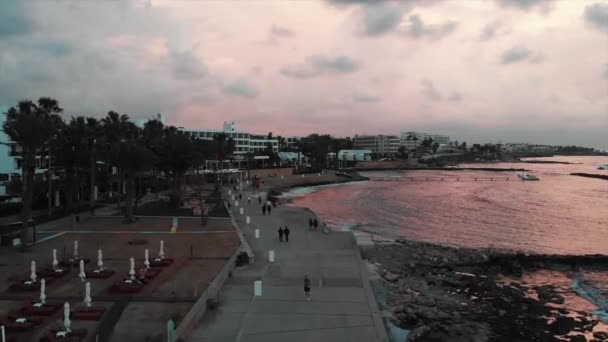 日落时分，带棕榈树和海滩设备的步行长廊鸟瞰图。在地中海附近与步行人的旅游区的无人机拍摄 — 图库视频影像