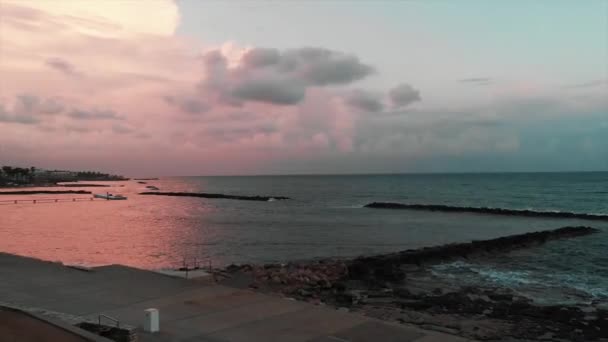 Luftaufnahme des felsigen Strandes mit touristischem Fußweg mit Palmen bei Sonnenuntergang — Stockvideo