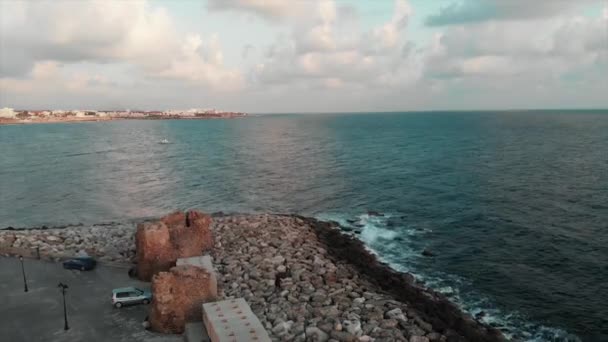 Drone atterrit à la marina avec la mer et le ciel bleu sur le fond à la journée ensoleillée d'été. Vue aérienne de la plage de rochers avec océan à l'horizon . — Video