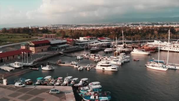 Drone shot of Paphos city with harbor and lighthouse. Aerial view of quay with yachts and fishing boats  with mountain landscape at background — Stock Video