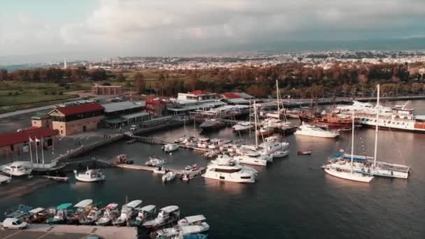 Drone flies through beautiful tourist quay with yachts and boats at city harbor. Aerial view of Cyprus island with lighthouse and tourist area — Stock Video