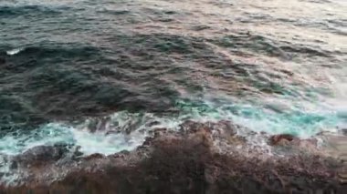 Siyah taşlar ve büyük deniz dalgaları ile kayalık kıyı boyunca uçan Drone kayalıklara çarpmak