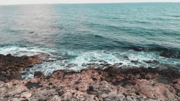 Luchtfoto drone uitzicht op de grote oceaan golven raken Rocky Beach en het creëren van wit schuim — Stockvideo