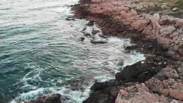 Vista aérea del mar tormentoso y grandes olas que golpean la playa rocosa con césped verde — Vídeo de stock