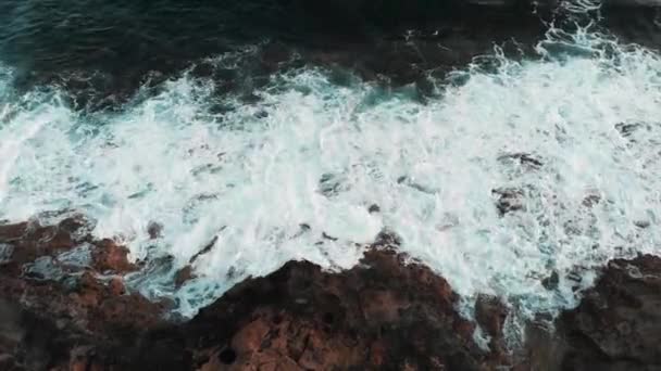 Letecký pohled na krásné mořské vlny, které dopadá a šíří se přes skalnatou pláž. Velké oceánské vlny vytvářející bílou pěnu a rozstřikování — Stock video