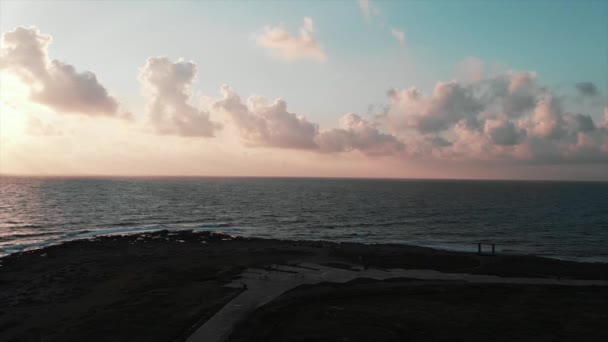 美丽的步行街鸟图, 游客在日落时穿过岩石海滩, 在地平线上走在海洋中 — 图库视频影像