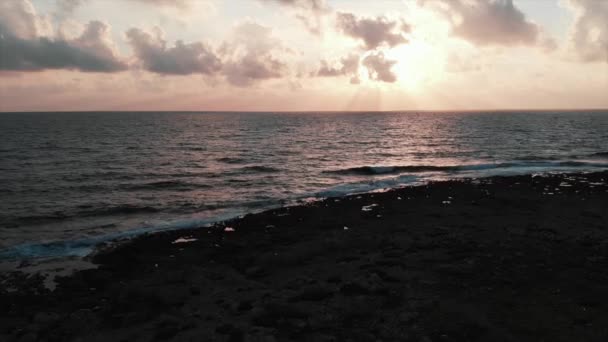 Vista aérea de la hermosa puesta de sol rosa con grandes olas del océano golpeando la playa rocosa durante la tormenta — Vídeo de stock