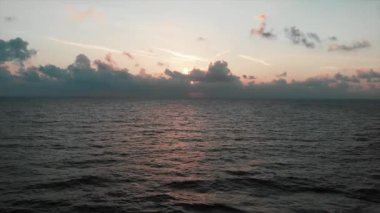 Drone güneş yolu ile pembe gün batımında muhteşem bulutlu gökyüzü ile güzel okyanus üzerinden uçar