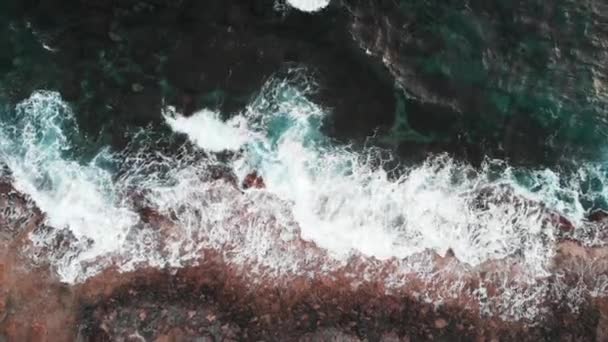 Drone Draufsicht auf große schöne Ozeanwellen, die weißen Schaum erzeugen, spritzen und mit Felsen kollidieren — Stockvideo