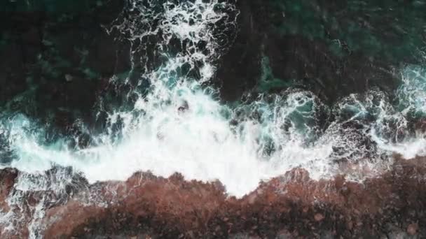 Aerial top view of stormy ocean with huge white waves hitting rocky seashore — Stock Video