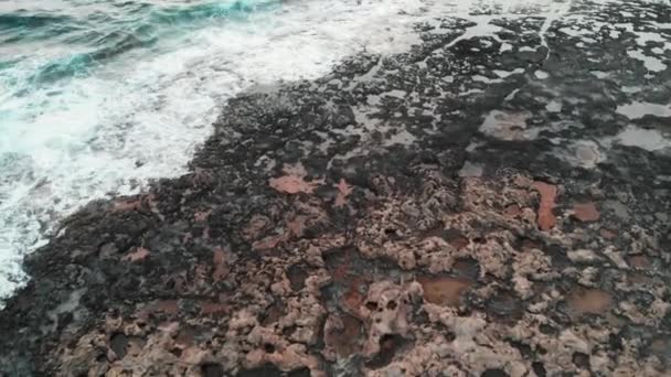 Vzdušný pohled na skalnaté pobřeží s velkými vlnami oceánu na růžovém nádherném slunci — Stock video