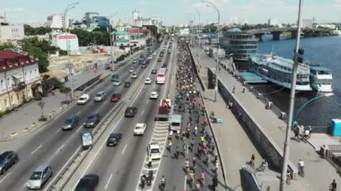 Binlerce çekici bisikletçi güneşli yaz gününde uluslararası bisiklet gününde şehir Dnipro nehir rıhtım boyunca sürücü. Havadan insansız hava aracı görünümü