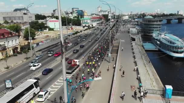 Flygvy över kolonnen av unga attraktiva cyklister som rider längs stadskajen på internationella Cykeldag — Stockvideo