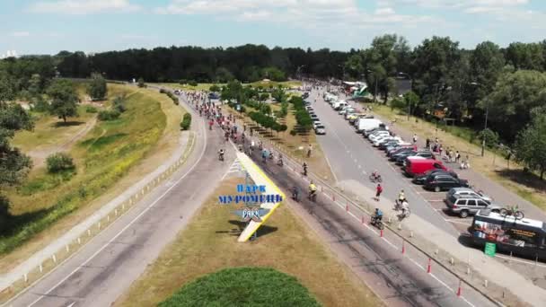 Grupp unga lyckliga sportiga cykel ryttare i Bright fritidskläder ridning i Muromets Park — Stockvideo