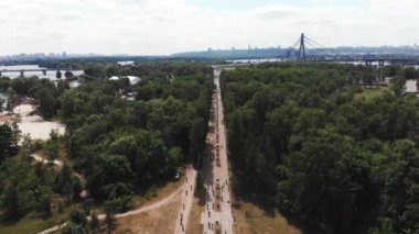 Drone güzel doğa ve bisiklet yolu ile yeşil park üzerinden uçar. Büyük şehir parkında niçin bisiklete binen bir grup bisikletçi