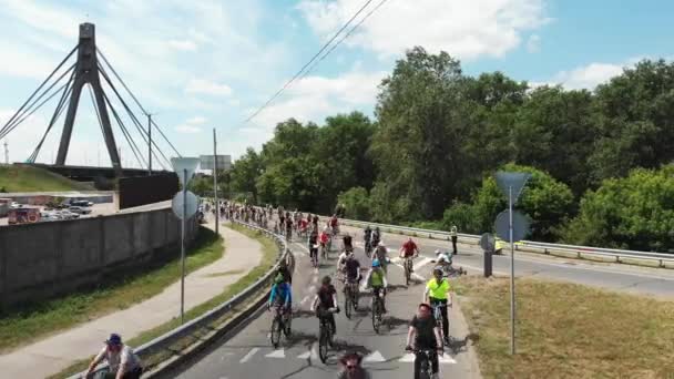 Kijów / Ukraina-czerwiec, 1 2019 Atrakcyjny szczęśliwy rowerzysta w jasnych ubraniach przejeżdżający przez zielony park miejski w wietrzny letni dzień. Widok drona z powietrza — Wideo stockowe