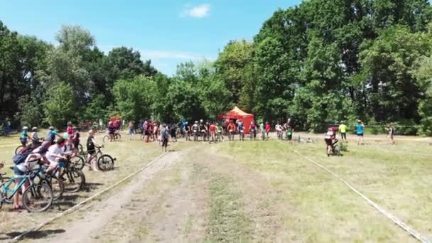 キエフ/ウクライナ-2019年6月1日公園でマウンテンバイクレースが始まるのを待っている若いスポーツサイクリストのグループにドローンが飛び立つ — ストック動画