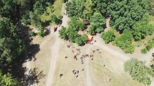 Luftaufnahme des Startbereichs des Mountainbike-Rennens mit Radfahrern, die sich auf den Wettbewerb im grünen Wald vorbereiten — Stockvideo