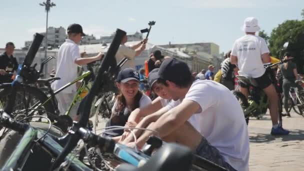 Киев / Украина-1 июня 2019 г. Молодые счастливые велосипедисты сидят рядом с велосипедами, разговаривают и улыбаются на велопараде. Медленное движение — стоковое видео