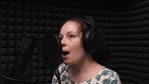 Chica atractiva vocalizando en estudio de música de grabación. Retrato de niña cantando — Vídeos de Stock