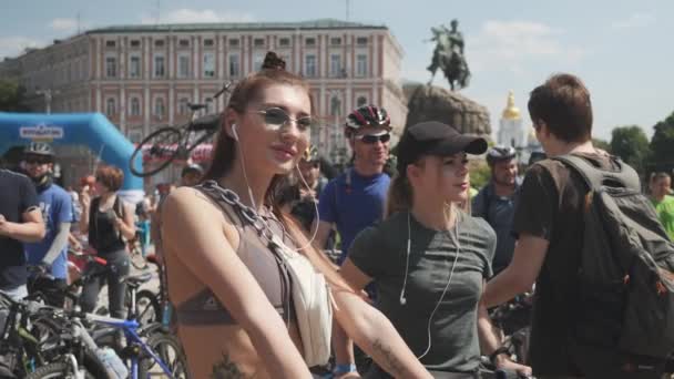 基辅/乌克兰-2019年6月,1 年轻有吸引力的热铁人三项运动员女孩与耳机在运动胸罩是站在她的自行车附近,享受阳光在自行车日。慢动作 — 图库视频影像
