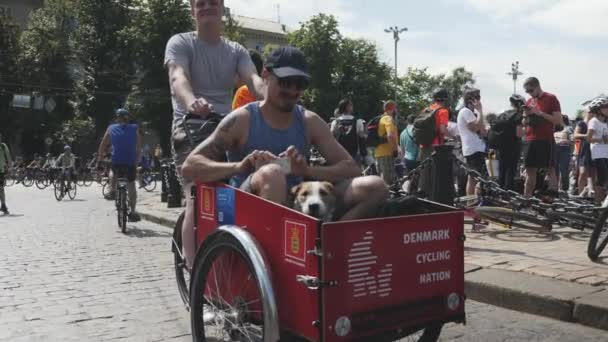 Kiev/Ukraina-juni, 1 2019 rolig man på Cycling Parade. Porträtt av pojke med hund sittande i vagn. Ung pojke med hund på Bicycle Parade. Man i cykelvagn. Slow motion — Stockvideo