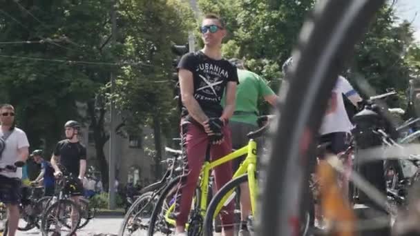 基辅/乌克兰-2019年6月1日 男孩坐在自行车上。人正站在自行车游行上。在基辅的自行车游行中戴着太阳镜的运动男孩的肖像 — 图库视频影像