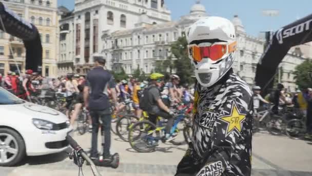 Kiev/Ukrayna-Haziran,1 2019 Turuncu maskeli ve büyük beyaz kasklı dağ bisikletçisini kameraya yakınlayın. Dağ bisikletine binen genç çocuğun portresi. Pompa parça binici yakın. Kiev'de bisiklet günü. Yavaş çekim — Stok video