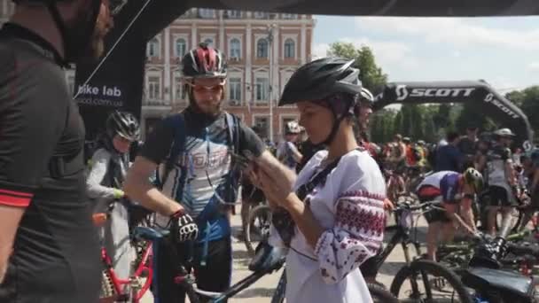 Kyjev/Ukrajina-červen, 1 2019 ukrajinská dívka s pohledem na telefon. Žena v národním kostýmu se usmívá na kameru. Portrét dívky v cyklistice v Kyjevě. Cyklistický koncept — Stock video