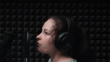 Profesyonel vokal stüdyosunda genç çekici kadın kayıt şarkısı. Sevimli kız müzik stüdyosunda şarkı söylüyor. Kayıt provası