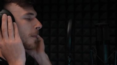 Çekici çocuğun portresi müzik dinlemektir. Genç erkek şarkıcı kulaklıkla şarkı dinliyor. Vokal müzik kayıt stüdyosu