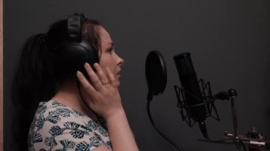 Romantik pop disko kadın şarkıcı şarkı başlar. Kulaklıklı kız profesyonel kayıt stüdyosunda şarkı prova