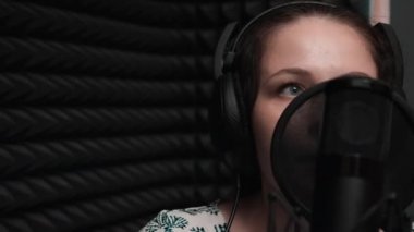 Vokal stüdyosunda mavi gözlü çekici kız yakın. Kayıt stüdyosunda şarkı kaydeden genç kadın. Kayıt takibi. Vokal stüdyo provası