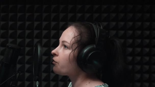 Joven mujer atractiva grabación canción en estudio vocal profesional. Linda chica está cantando canción en el estudio de música. Ensayo de grabación — Vídeos de Stock