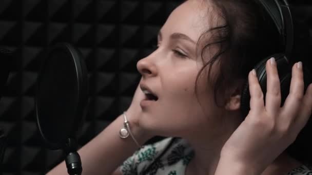 Extra close-up van het jonge meisje zingende lied. Close-up van aantrekkelijke vrouw in hoofdtelefoon. Close-up van mooi meisje met blauwe ogen — Stockvideo