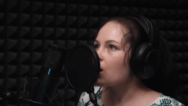 Jonge brunette meisje met blauwe ogen emotioneel zingen op opnamestudio. Muziekopname. Vocale repetitie — Stockvideo