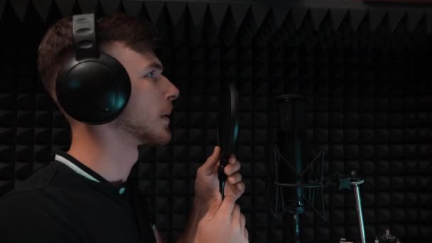 Jeune beau garçon caucasien se prépare pour l'enregistrement de chanson. Un chanteur dans un casque commence à chanter au studio d'enregistrement — Video