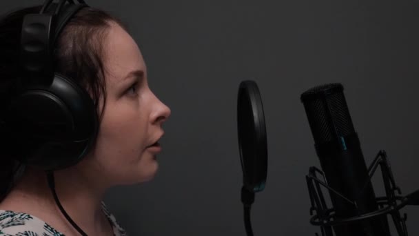 Zblízka pohled na roztomilou dívku ve sluchátkách zpívá písničku. Emocionální dramatický zpěv. Profesionální vokální Studio — Stock video