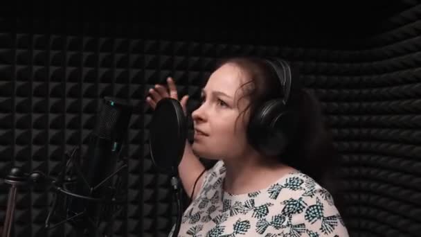 Brunett flicka känslomässiga sång till mikrofon i Vocal Studio. Begåvade unga kvinnliga artist är inspelning Song med professionell musikutrustning i Vocal Studio. — Stockvideo