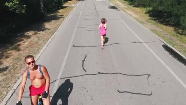 Sportive brunette female runner with trained legs is practicing running technique in park. Attractive girl in pink clothes running in park at hot day. Running workouts — Stock Video