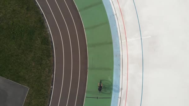 Drone top view of female cyclist on road bike training at velodrome. Young cycling girl is riding slowly on cycling path at velodrome. Cycling concept — Stock Video