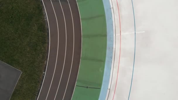 Young cycling girl is riding slowly on cycling path at velodrome. Drone top view of female cyclist on cycling track — Stock Video