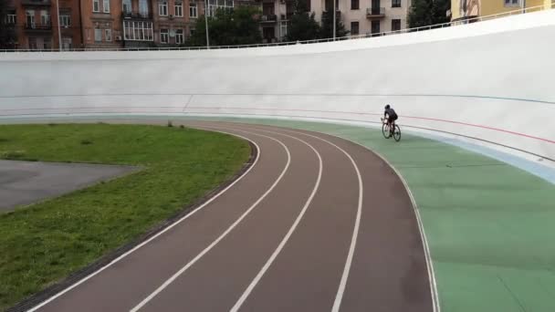 Молодая привлекательная женщина-велогонщица тренируется на велодроме. Спортивная девушка в шлеме едет на велосипедной дорожке. Женщина на дорожном велосипеде учится ездить — стоковое видео