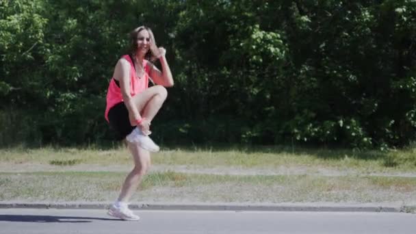 Jovem mulher atraente realizando dança engraçada. Menina caucasiana bonito brincando no parque. Menina bonita rindo e dançando. Mulher se divertindo no parque — Vídeo de Stock