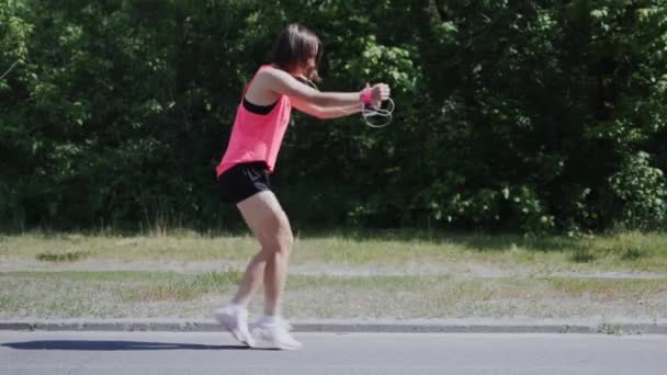 Attraktiv Sportiv tjej som dansar i parken. Ung flicka utför löjlig dans och lurar runt. Söt flicka i rosa skjorta skratta och ha kul. Slow motion — Stockvideo