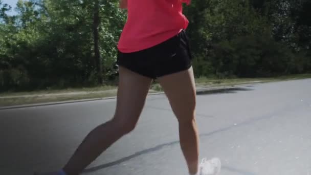 Мотивированная молодая бегунья, тренирующаяся в парке. Концентрированная спортивная женщина бегает по парку. Привлекательная стройная девушка с тренированными ногами делает упражнения. Концепция запуска. Медленное движение — стоковое видео